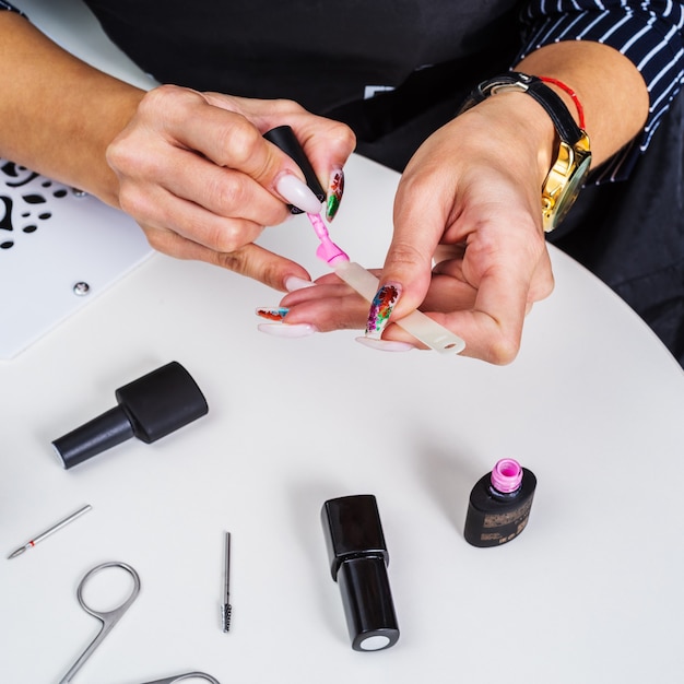 Trabajador en salón de uñas pinta uñas de extensión artificial en el lugar de trabajo Vista desde arriba