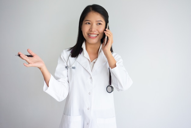 Trabajador de salud asiática positiva hablando por teléfono