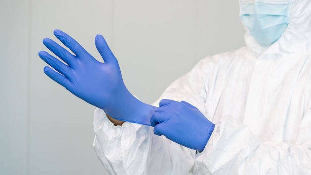Foto un trabajador de la salud se prepara poniéndose guantes para tratar a los pacientes con covid. la enfermera usa un traje de protección ppe