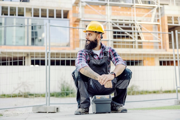 Un trabajador sentado en una caja de herramientas y esperando un paseo en el sitio de construcción