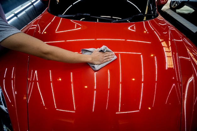 Trabajador de servicio automotriz aplicando nano revestimiento en el detalle de un automóvil