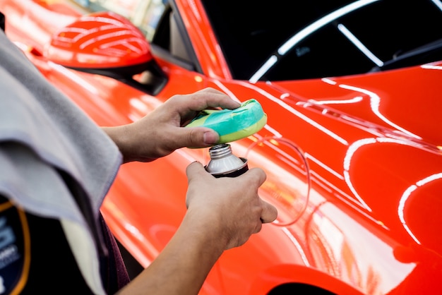 Trabajador de servicio de automóviles aplicando un nano recubrimiento en un detalle de automóvil