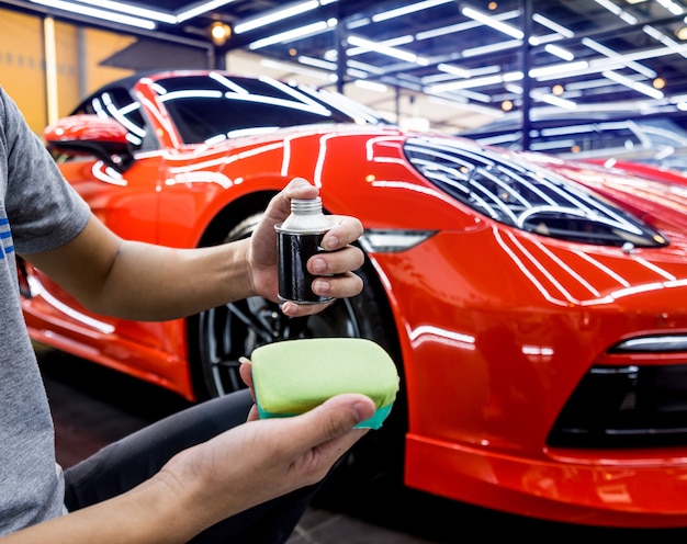 Trabajador de servicio de automóviles aplicando un nano recubrimiento en un detalle de automóvil