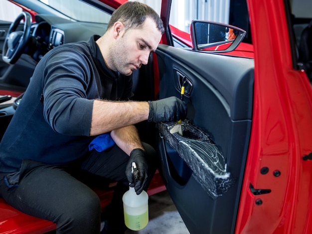 Foto el trabajador del servicio de automóviles limpia el interior con un cepillo especial