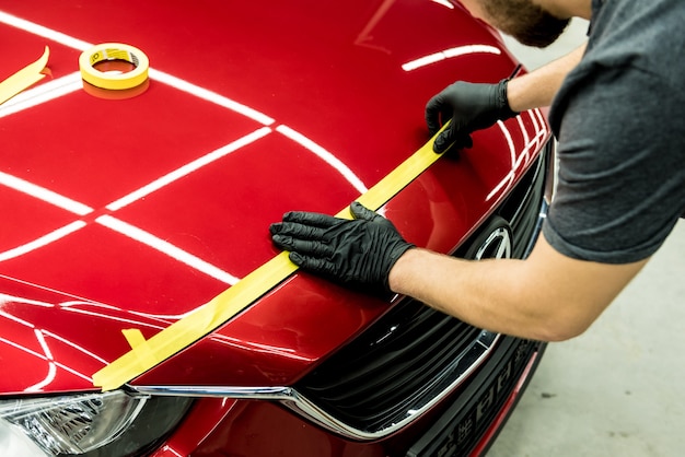 Trabajador de servicio de coche aplicando cinta protectora en el coche