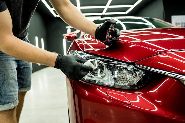 Trabajador de servicio de coche aplicando nano revestimiento en un detalle de coche.