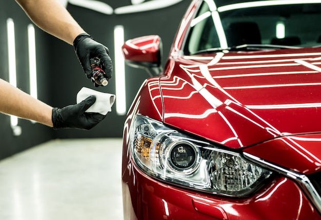 Trabajador de servicio de coche aplicando nano revestimiento en un detalle de coche.