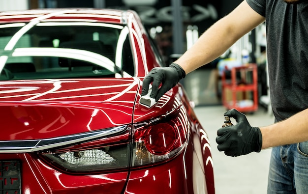 Trabajador de servicio de coche aplicando nano revestimiento en un detalle de coche.