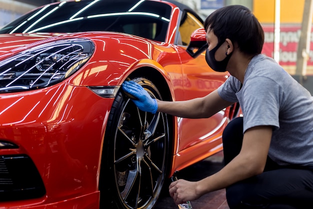 Trabajador de servicio de coche pulido de ruedas de coche con tela de microfibra.