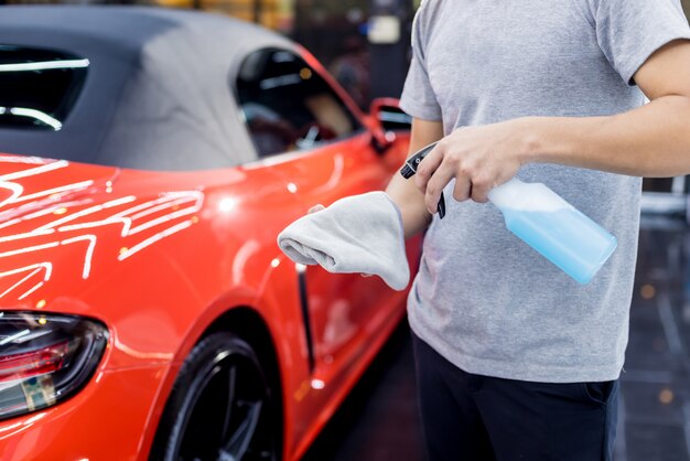 Trabajador de servicio de coche pulido de ruedas de coche con tela de microfibra.