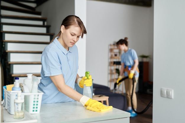 Foto trabajador del servicio de limpieza limpiando el polvo de los muebles