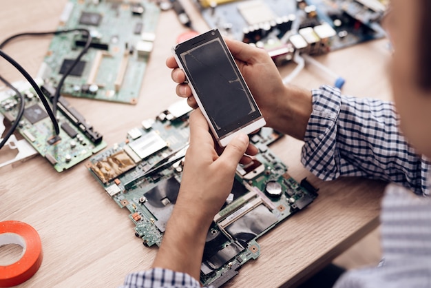 Trabajador de servicio en la mano y mira el teléfono roto