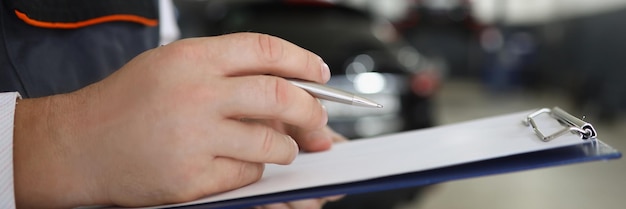 Trabajador de servicio masculino llenar la documentación de mantenimiento después de reparar el coche