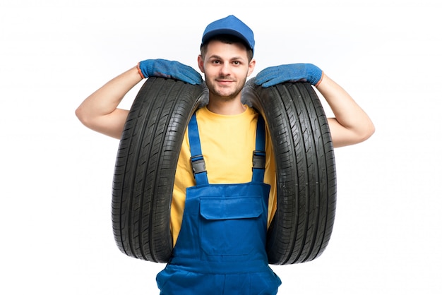 Trabajador de servicio de neumáticos en uniforme azul tiene neumático de coche