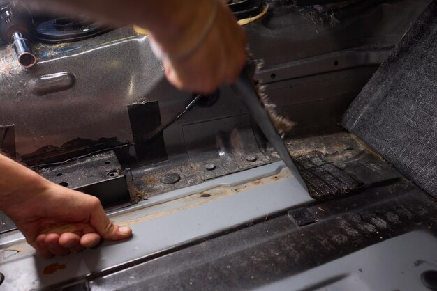 Trabajador de servicio de tuning instala material de aislamiento acústico dentro del interior del automóvil