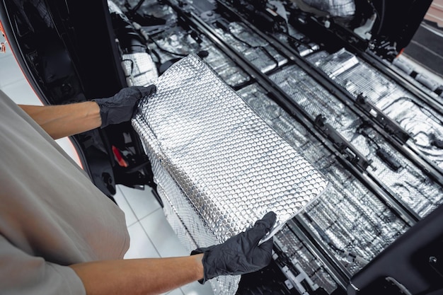 El trabajador del servicio Tunning instala material de insonorización dentro del interior del coche