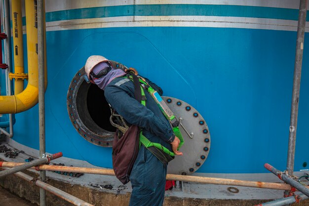 Trabajador de sexo masculino está parado por aire fresco del ventilador de seguridad del espacio confinado del área del aceite del tanque de combustible.