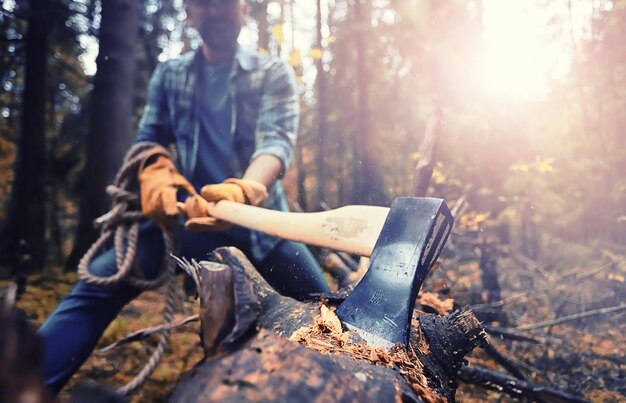 Trabajador de sexo masculino con un hacha cortando un árbol en el bosque.