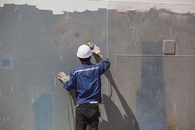 Trabajador de sexo masculino pulir el tanque de los blancos de la pintura del color al aceite.