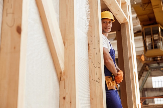 Trabajador de sexo masculino sonriente de pie dentro de la cabina de construcción de madera