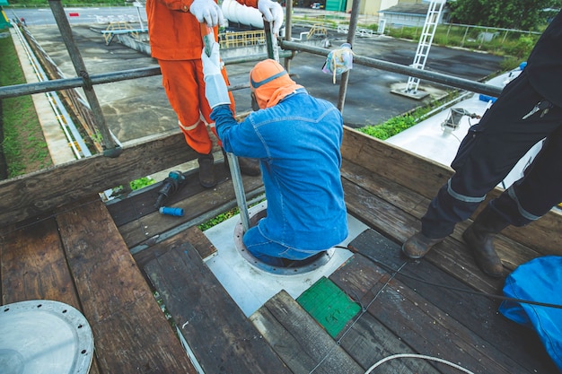 Trabajador de sexo masculino sube al interior del tanque de inspección visual de almacenamiento de la escalera hacia el espacio confinado.