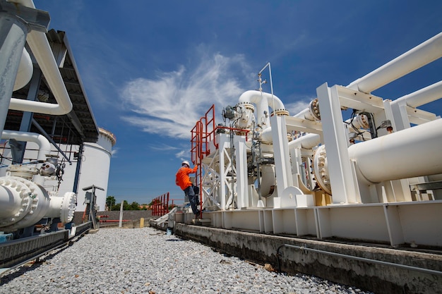 Trabajador de sexo masculino subir escaleras inspección en tubos largos de acero y codo de tubería en la fábrica de petróleo de la estación durante la válvula de refinería de la industria de petróleo y gas de tubería de registro de verificación visual