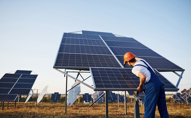 Trabajador de sexo masculino en uniforme azul al aire libre con baterías solares en un día soleado.