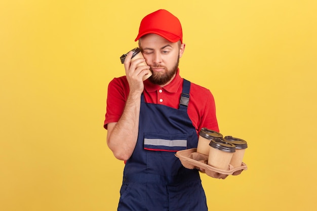 El trabajador se siente somnoliento después de un trabajo duro de pie con los ojos cerrados tomando una siesta sosteniendo tazas de café