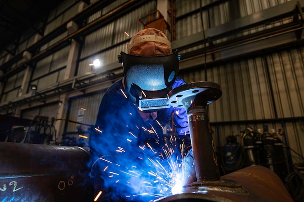 El trabajador de soldadura de metal es parte de la construcción de tuberías de boquillas de maquinaria, petróleo y gas.