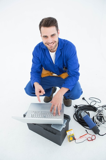 Foto trabajador sonriente del construciton que señala en la computadora portátil