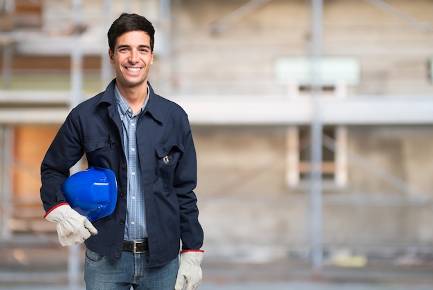 Trabajador sonriente delante de un sitio de construcción. Gran espacio de copia