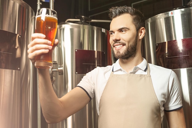 Trabajador sonriente inspeccionando cerveza en la cervecería