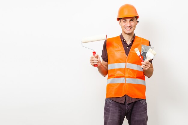 Trabajador sonriente en uniforme protector y casco protector aislado en blanco