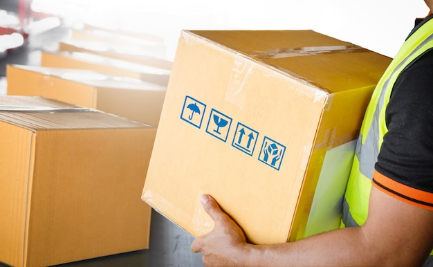 Foto trabajador sosteniendo un paquete cajas de paquetes clasificación en cinta transportadora suministros almacén envío