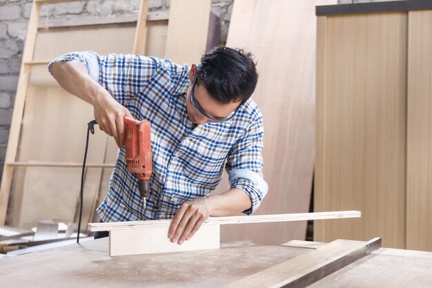 Trabajador en el taller de carpintería instalando pernos con destornillador