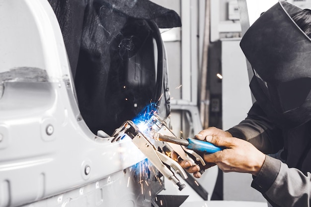 Trabajador de taller de carrocería soldando carrocería de automóvil Trabajo con soldadura de dióxido de carbono