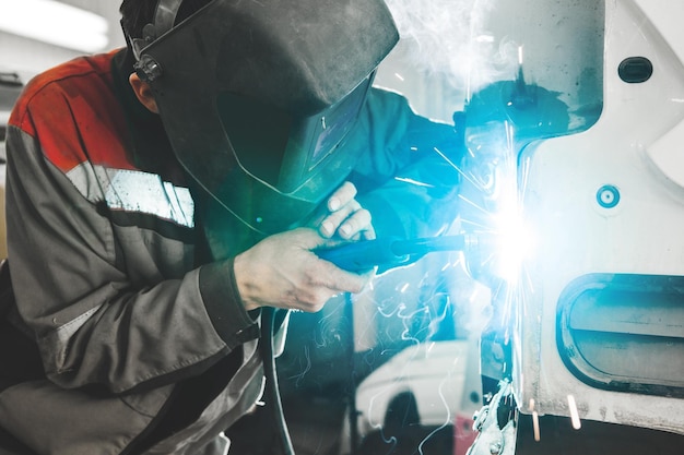 Trabajador de taller de carrocería soldando carrocería de automóvil Trabajo con soldadura de dióxido de carbono