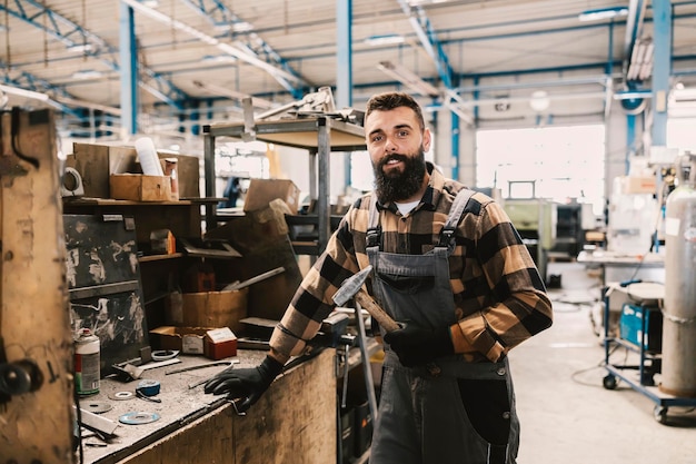 Un trabajador del taller sosteniendo un martillo y sonriendo a la cámara en la tienda