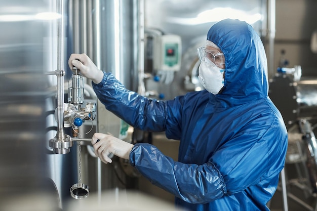 Trabajador con traje protector y equipo operativo de mascarilla en una fábrica de productos químicos