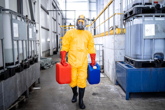 trabajador con traje protector y máscara de gas que transporta productos químicos dentro de la producción de galvanizado de zinc