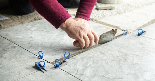 Foto trabajador usando espátula y poniendo pegamento en el piso