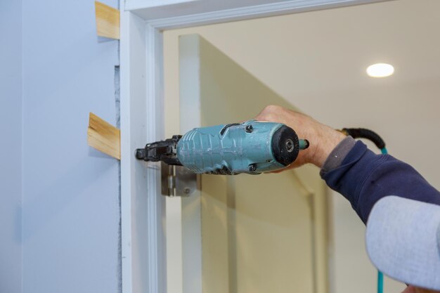 Trabajador usando pistola de clavos instalando la puerta interior