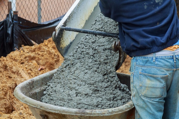 Trabajador vertiendo cemento del carro al piso en el sitio de construcción