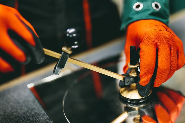Trabajador vidriero cortando vidrio con cortador de vidrio de brújula en un taller Industria