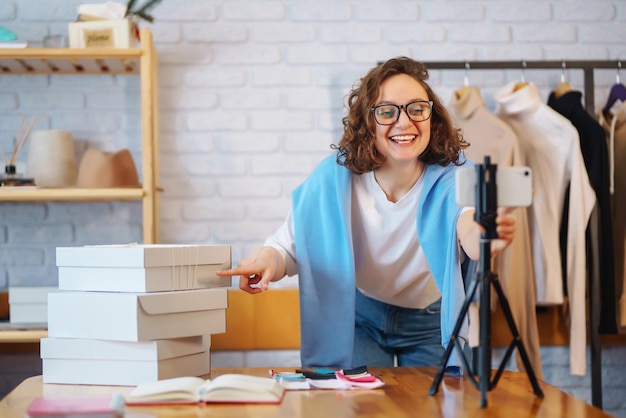 Foto trabajadora de almacén vendedora dropshipping propietaria de una pequeña empresa grabando nuevo contenido para vlog