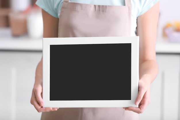 Foto trabajadora de la barra de leche femenina sosteniendo una pizarra negra sobre fondo borroso