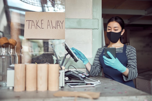 Trabajadora de café femenino tomando pedidos en línea en interiores