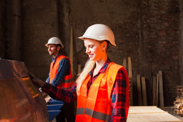 Trabajadora carpintera profesional en el taller Trabajadores con casco protector, ropa y guantes Concepto de la industria de la carpintería