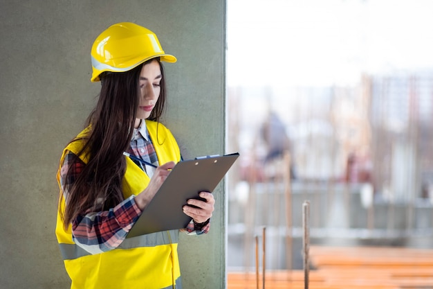 Trabajadora de la construcción femenina con un portapapeles en la mano inspecciona el proceso de construcción