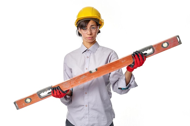 Trabajadora de la construcción con herramienta de nivel en el fondo de la pared de la casa